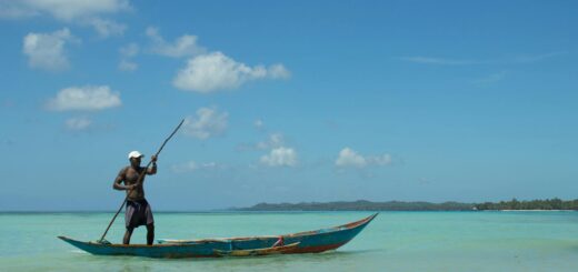 A Malagasy fisherman paddles a traditional pirogue on the clear blue waters of Madagascar's east coast