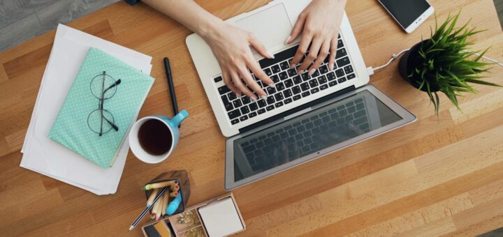 Modern desk workspace with laptop coffee and notebooks, top-down view
