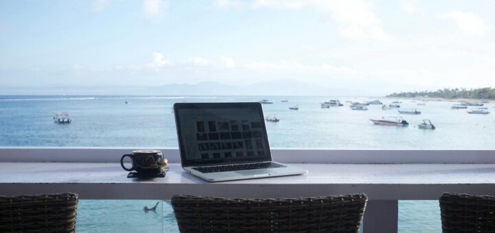 Laptop and coffee mug on a beachside workspace overlooking the ocean